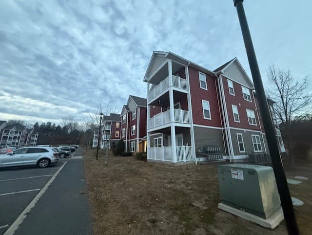 A row of Brook Hill Village apartment buildings at dusk with resident parking in the foreground