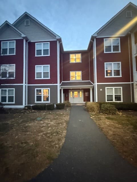 Front elevation of a Brook Hill Village building with lit apartment windows