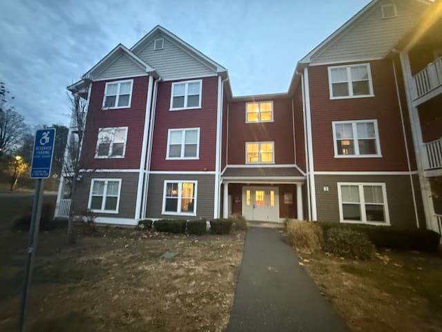 Front of a Brook Hill Village building at dusk with an accessible parking sign in the foreground
